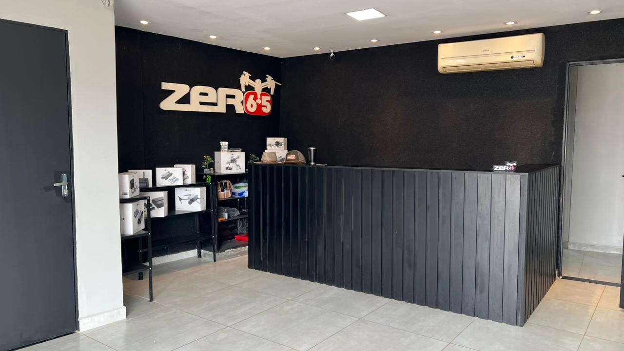 Recepção da loja Zero65 Drones com balcão de atendimento, produtos e logomarca na parede