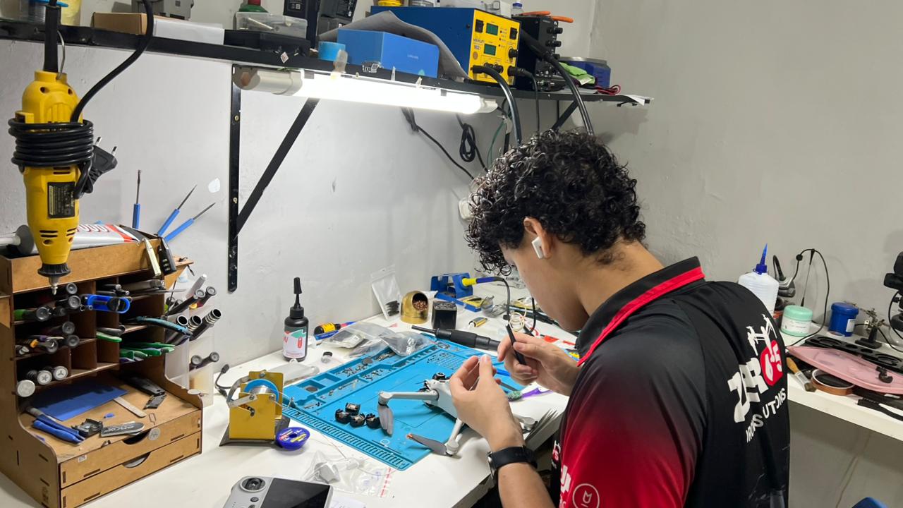 Técnico da Zero65 Drones em trabalho de microeletrônica e solda no reparo de um drone DJI